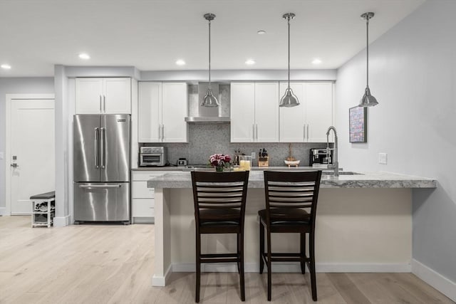 150 W Broadway Unit 203, Boston, MA 02127 - kitchen with high quality fridge, wall chimney range hood, light wood-type flooring, white cabinets, and tasteful backsplash