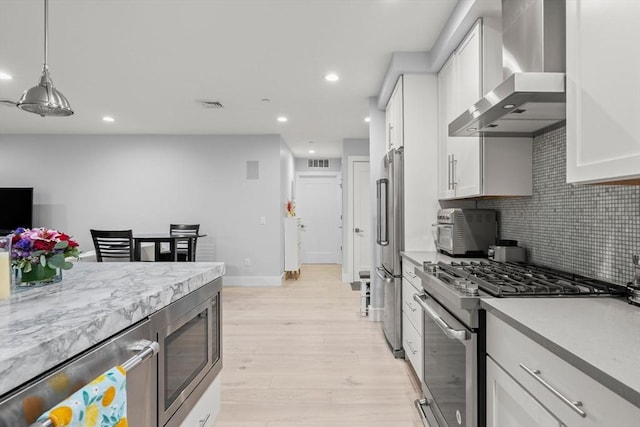 150 W Broadway Unit 203, Boston, MA 02127 - kitchen featuring appliances with stainless steel finishes, wall chimney range hood, backsplash, light wood-style floors, and recessed lighting