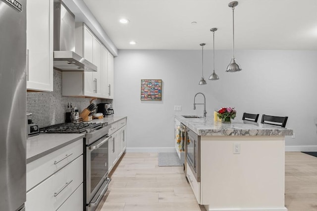 150 W Broadway Unit 203, Boston, MA 02127 - kitchen featuring wall chimney range hood, appliances with stainless steel finishes, light wood finished floors, decorative backsplash, and recessed lighting