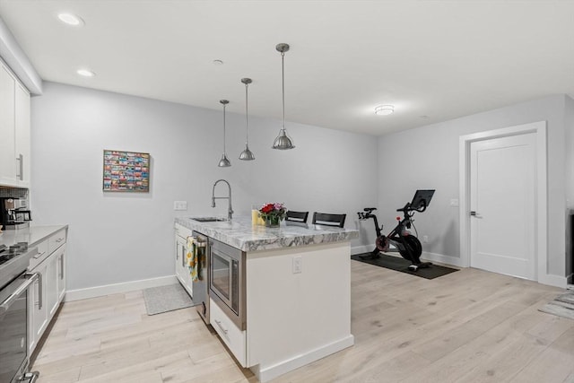 150 W Broadway Unit 203, Boston, MA 02127 - kitchen featuring light wood-type flooring, white cabinets, light stone countertops, appliances with stainless steel finishes, and recessed lighting