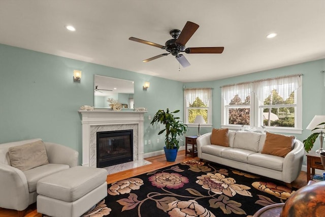 living room with ceiling fan, a high end fireplace, a wealth of natural light, and hardwood / wood-style floors