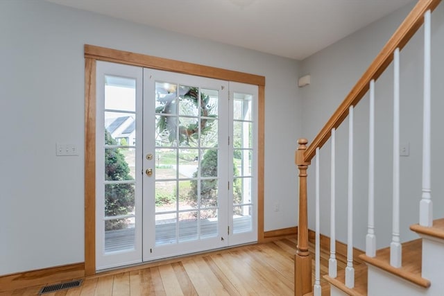 entryway featuring wood-type flooring, baseboards, visible vents, and stairway