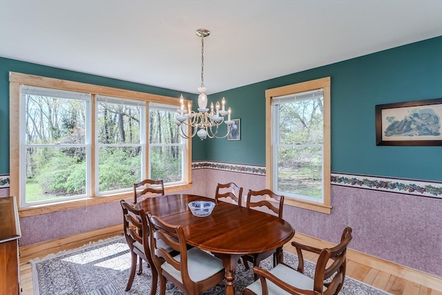 dining space featuring a chandelier, wainscoting, and wood finished floors