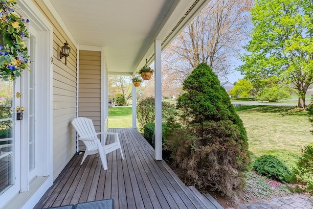 wooden terrace featuring a lawn and a porch