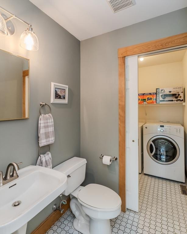 half bath featuring visible vents, a sink, tile patterned floors, and toilet