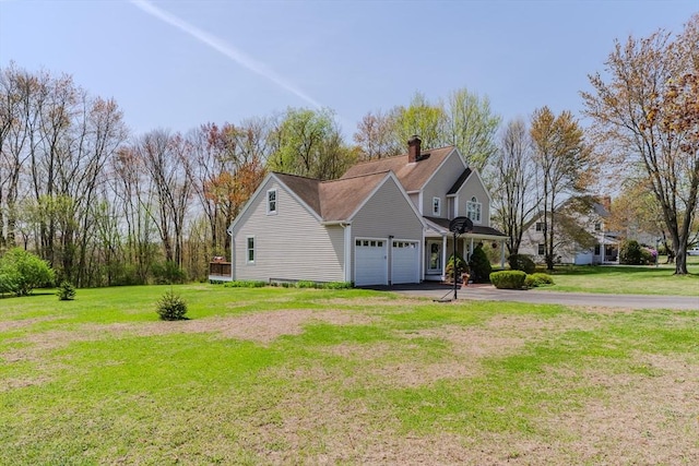 view of side of property with a garage, a chimney, a lawn, and driveway