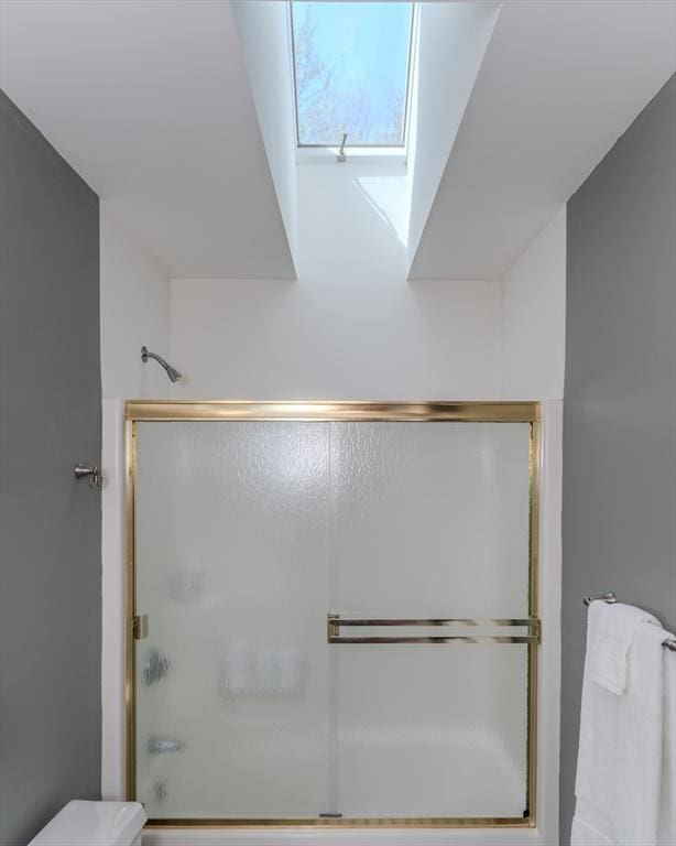 bathroom with toilet and combined bath / shower with glass door
