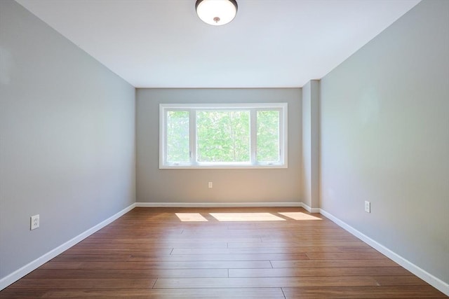 spare room featuring baseboards and hardwood / wood-style flooring