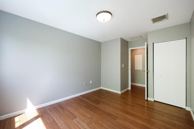 unfurnished bedroom with wood finished floors, baseboards, and a closet