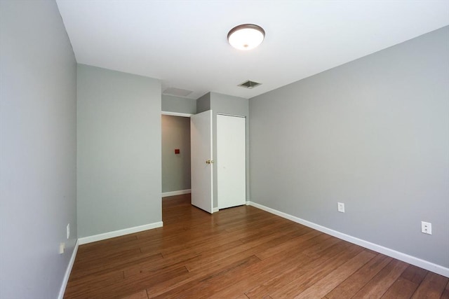 unfurnished bedroom with wood finished floors, baseboards, and a closet