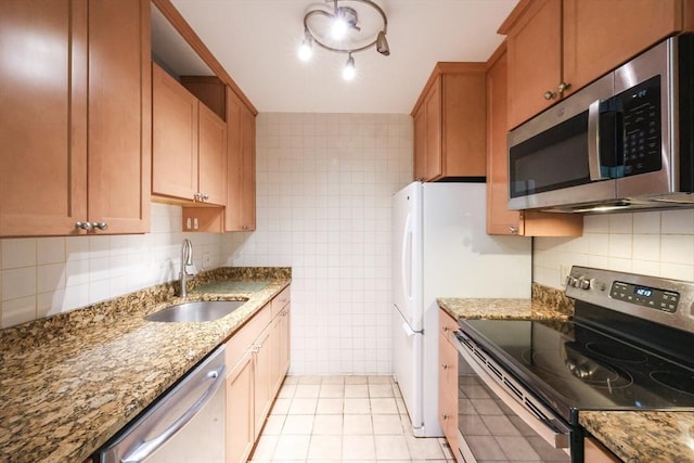 kitchen featuring appliances with stainless steel finishes, a sink, light tile patterned floors, backsplash, and light stone counters
