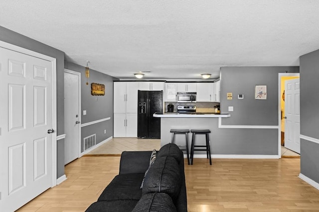 living room with a textured ceiling and light hardwood / wood-style floors