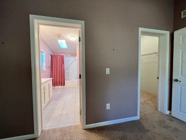 hallway featuring light carpet and a skylight