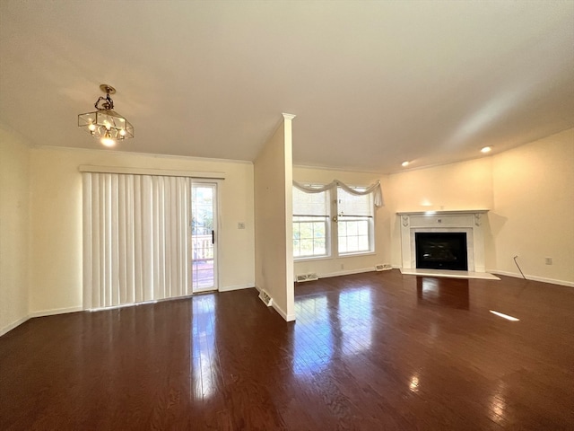 unfurnished living room featuring a chandelier, crown molding, and dark hardwood / wood-style floors