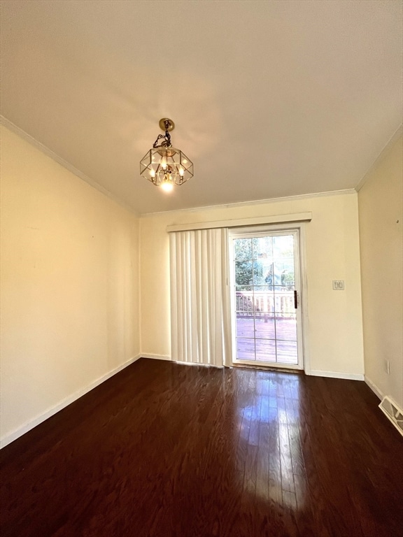 unfurnished room featuring a notable chandelier, ornamental molding, and dark hardwood / wood-style floors