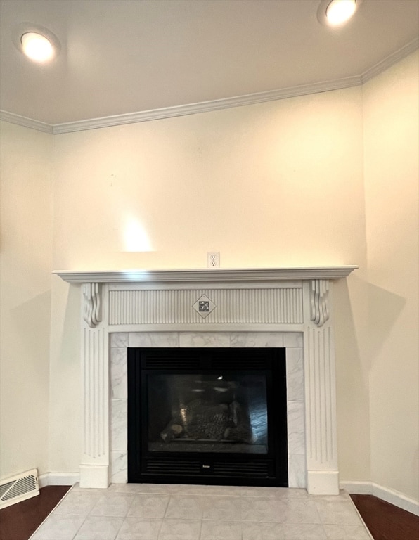 interior details with crown molding, a tile fireplace, and tile patterned floors