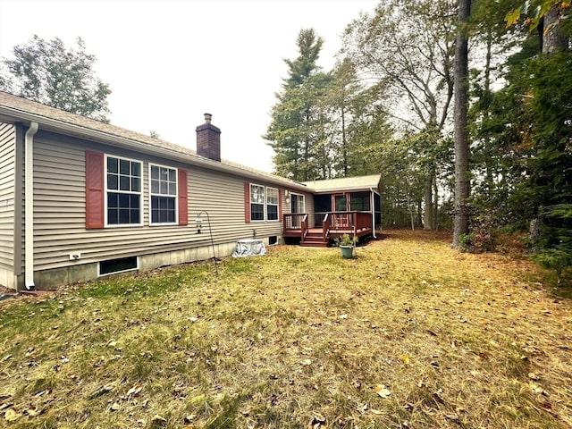 back of property with a deck and a yard