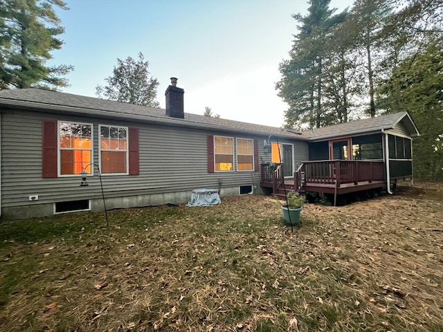 back of house featuring a wooden deck, a lawn, and a sunroom