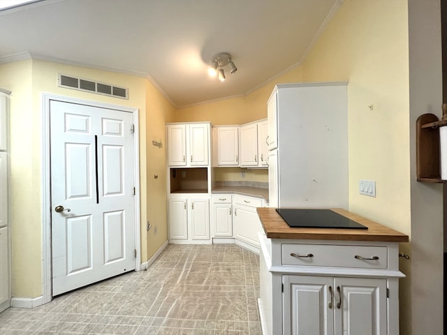 kitchen with wood counters, black electric cooktop, white cabinetry, vaulted ceiling, and crown molding