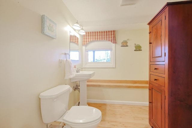 bathroom featuring toilet, wood finished floors, and baseboards