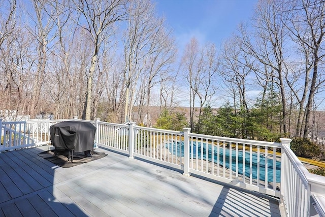 deck with a swimming pool and area for grilling