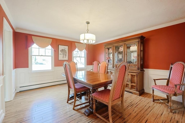 dining space featuring baseboard heating, wainscoting, light wood-style floors, and ornamental molding