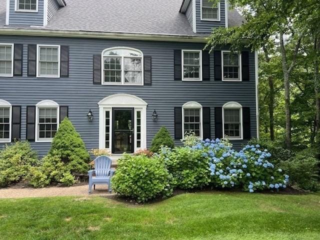 view of front of house featuring a front lawn and roof with shingles