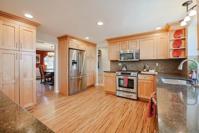 kitchen with a sink, stainless steel appliances, light brown cabinets, and light wood finished floors