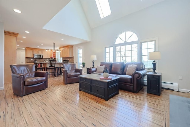 living area featuring a baseboard heating unit, recessed lighting, light wood-style flooring, a skylight, and high vaulted ceiling