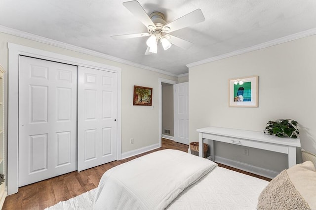 bedroom featuring ornamental molding, a ceiling fan, wood finished floors, a closet, and baseboards