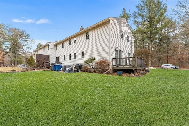 rear view of house with a deck, a chimney, and a yard