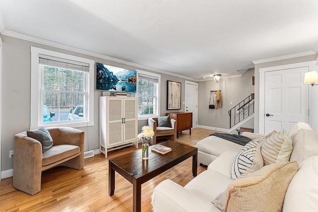 living area featuring visible vents, ornamental molding, light wood finished floors, baseboards, and stairs