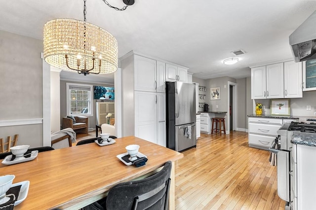 kitchen featuring light wood-type flooring, visible vents, white cabinetry, appliances with stainless steel finishes, and wall chimney exhaust hood