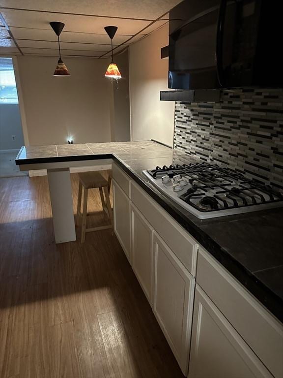 55 Alexander Ave, Dracut, MA 01826 - kitchen with stainless steel gas cooktop, black microwave, dark wood-type flooring, white cabinets, and decorative backsplash