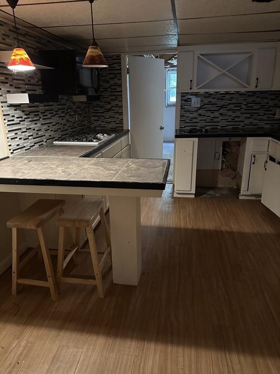 55 Alexander Ave, Dracut, MA 01826 - kitchen with backsplash, white cabinets, a kitchen breakfast bar, and dark wood-type flooring