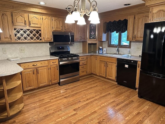 55 Alexander Ave, Dracut, MA 01826 - kitchen featuring black appliances, a chandelier, light wood-type flooring, pendant lighting, and backsplash