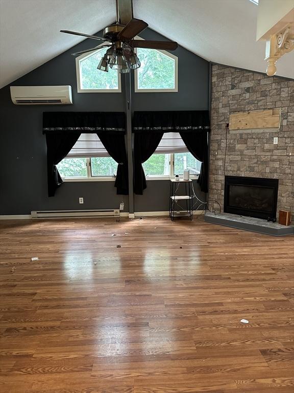 55 Alexander Ave, Dracut, MA 01826 - unfurnished living room with a wall mounted AC, a ceiling fan, vaulted ceiling, a baseboard heating unit, and wood finished floors