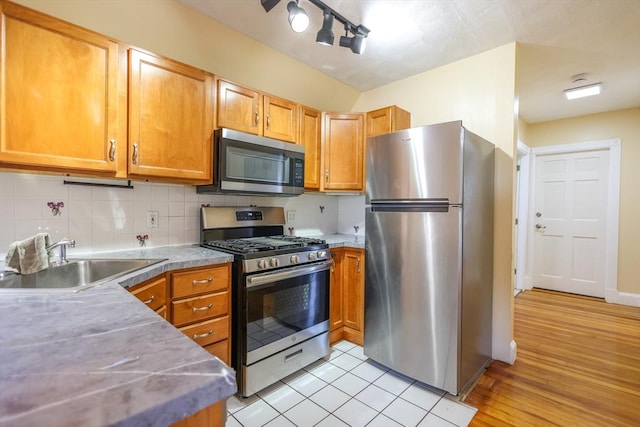 2A Hazel St Unit 3, Salem, MA 01970 - kitchen featuring stainless steel appliances, a sink, tasteful backsplash, light wood-style flooring, and brown cabinetry