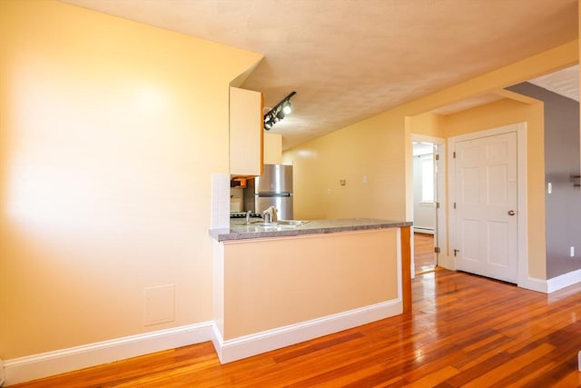 2A Hazel St Unit 3, Salem, MA 01970 - kitchen with freestanding refrigerator, baseboards, light wood-type flooring, white cabinetry, and a peninsula