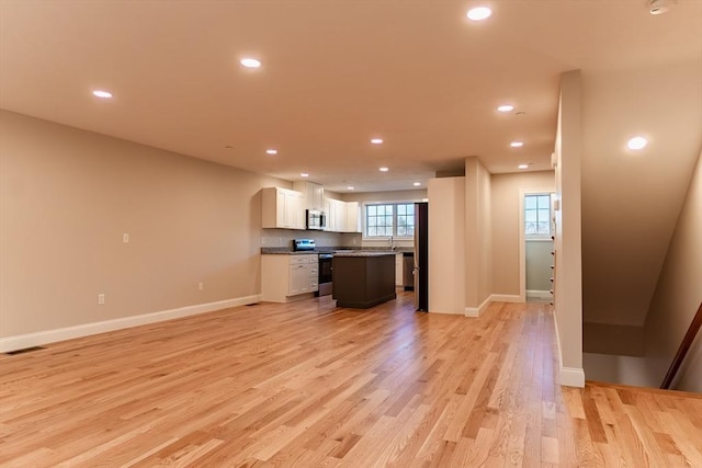 kitchen featuring a center island, white cabinets, sink, light wood-type flooring, and stainless steel appliances