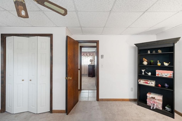 interior space with ceiling fan, carpet floors, a closet, and a drop ceiling