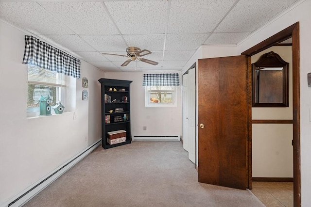 spare room with a paneled ceiling, light colored carpet, ceiling fan, and baseboard heating