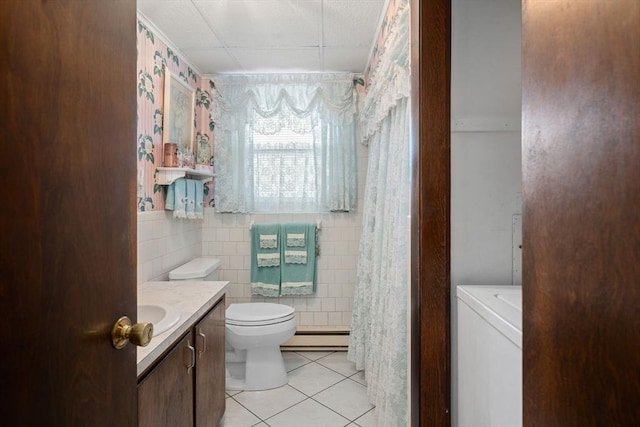 bathroom featuring baseboard heating, tile patterned flooring, tile walls, vanity, and washer / clothes dryer