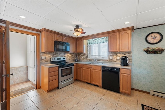 kitchen featuring light tile patterned flooring, a baseboard heating unit, sink, and black appliances