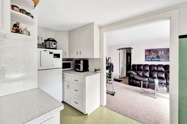 kitchen with light carpet, white refrigerator, and white cabinetry