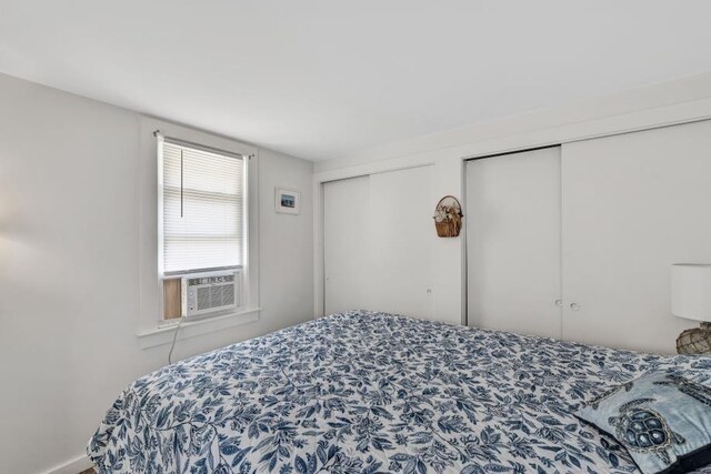 bedroom featuring cooling unit and two closets