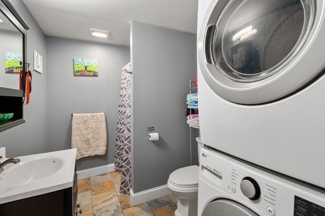 bathroom featuring toilet, stacked washer and dryer, and vanity