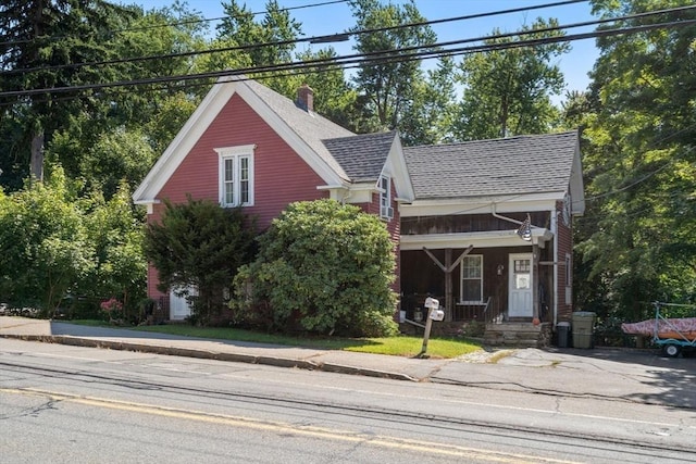 view of front facade featuring a shingled roof and a chimney