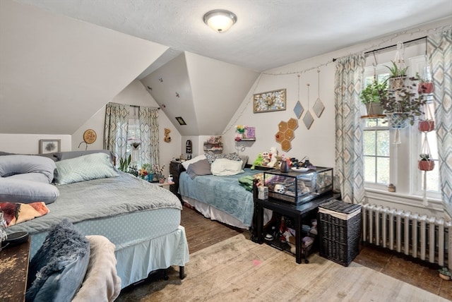 bedroom with radiator heating unit, vaulted ceiling, and hardwood / wood-style floors