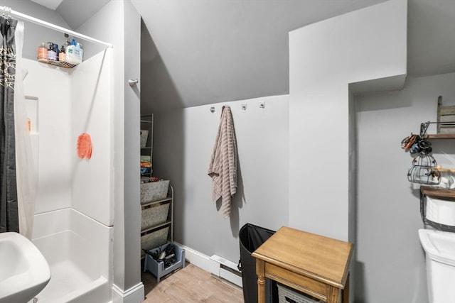 interior space with vaulted ceiling, a shower with curtain, hardwood / wood-style flooring, and sink